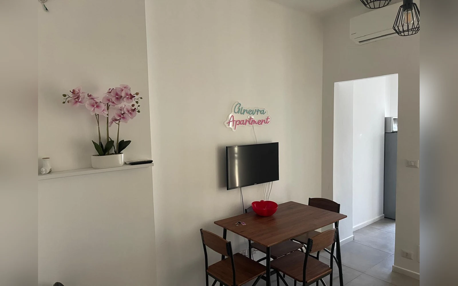 La zona pranzo della sala con tavolo, sedie e TV a schermo piatto